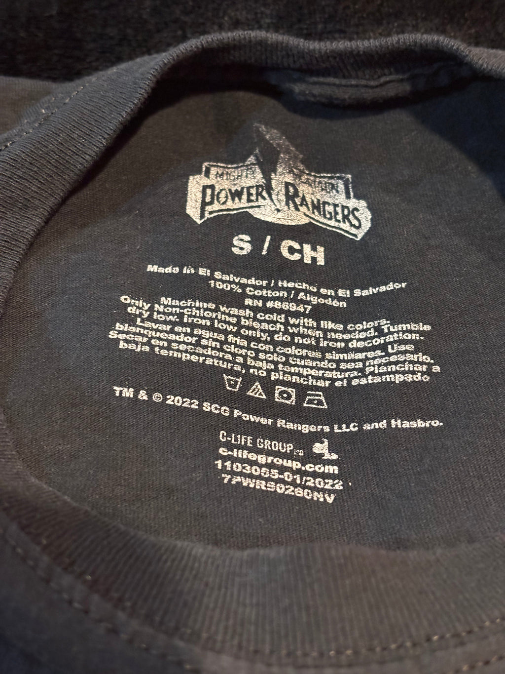 Inside tag showing size S, 100% cotton, made in El Salvador, and 2022 licensed design information