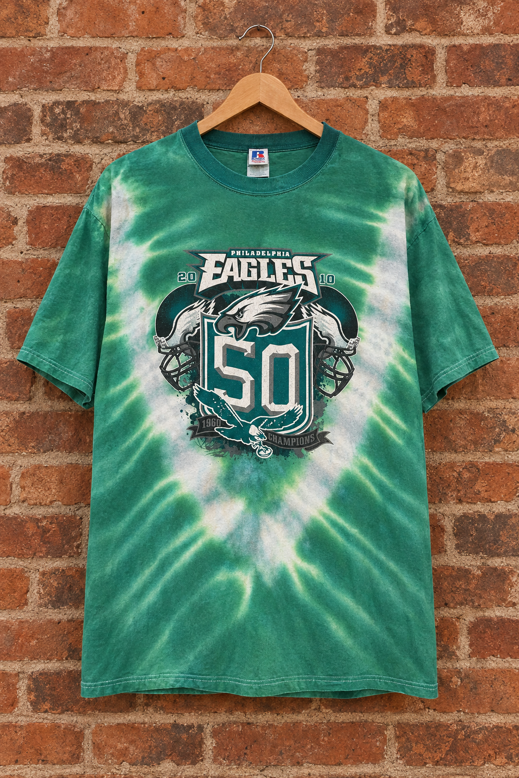 Revised Vickadelphia tie-dye shirt on a wooden hanger against a brick wall
